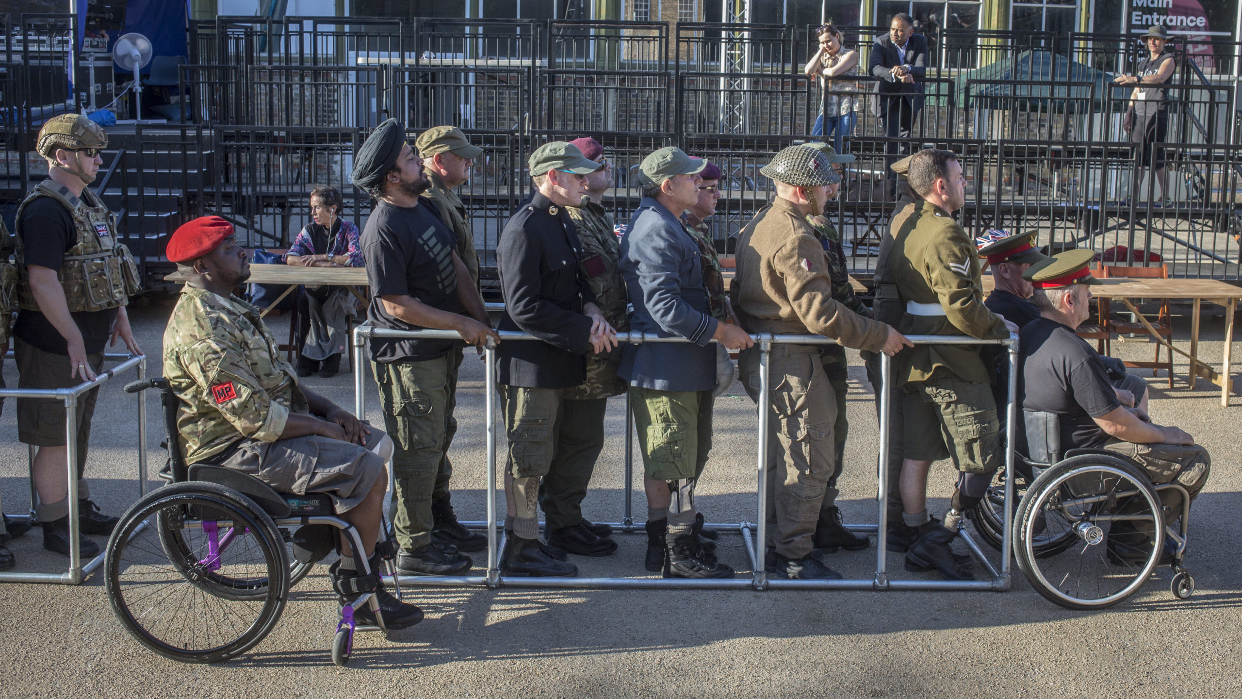 Five service people stand in a row holding on to the same metal bar, all looking forward.